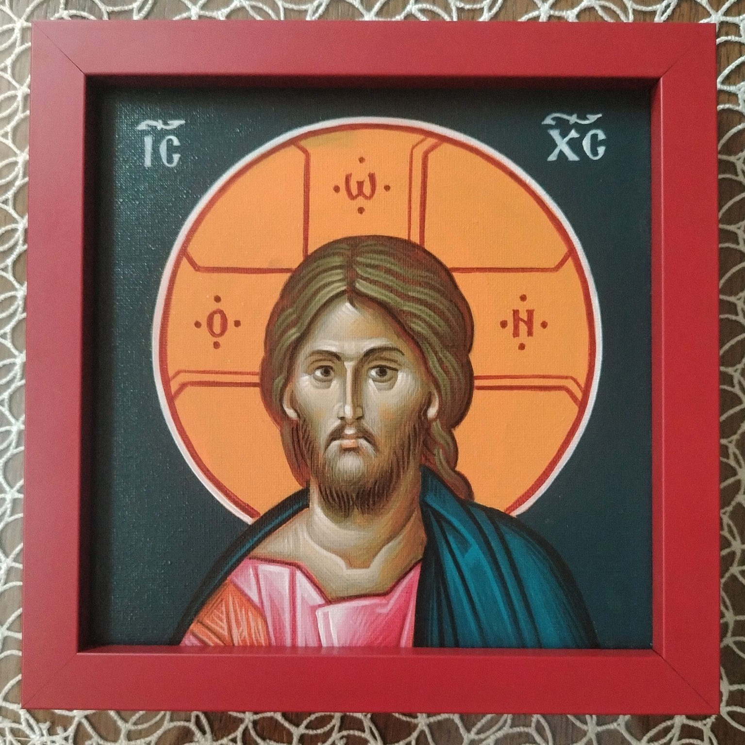 The original phone photograph of the framed icon resting on a lace-covered table
